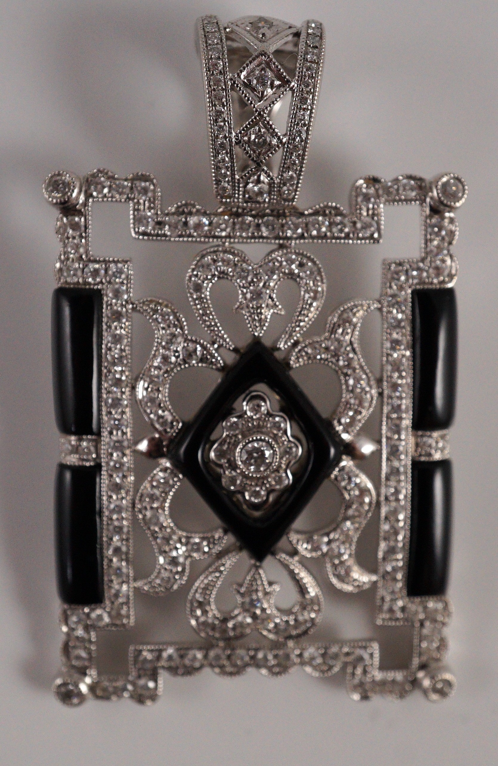 A modern 1920's style pierced 18k white gold, diamond and black onyx set rectangular pendant